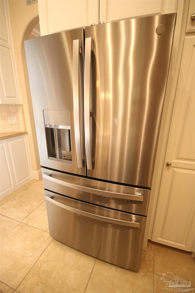 room details featuring white cabinets, light stone countertops, and stainless steel fridge