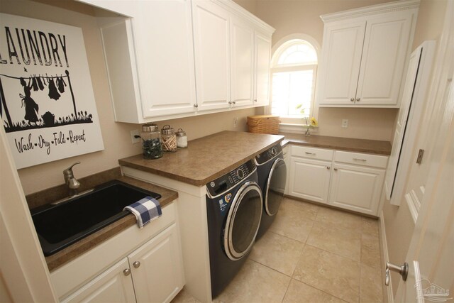 laundry area with washing machine and dryer, light tile patterned floors, cabinet space, and a sink