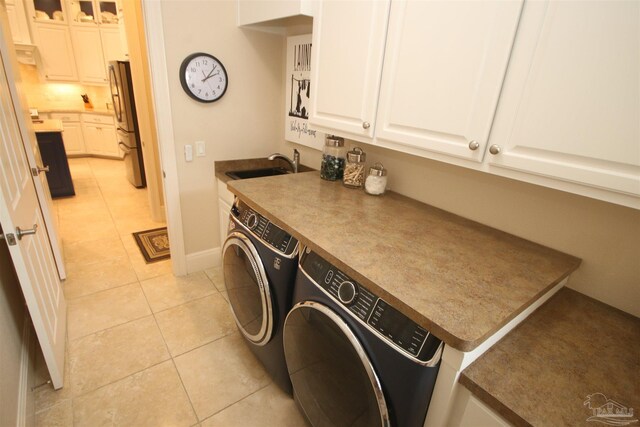 washroom with light tile patterned flooring, a sink, independent washer and dryer, and cabinet space