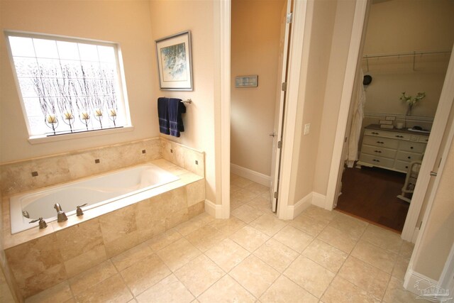 bathroom featuring a walk in closet, a garden tub, and tile patterned floors