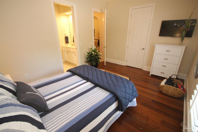 bedroom featuring baseboards, wood finished floors, arched walkways, and connected bathroom