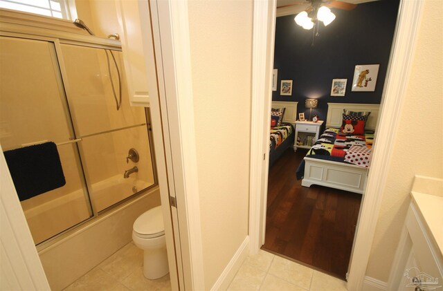 full bath featuring combined bath / shower with glass door, ceiling fan, baseboards, toilet, and tile patterned flooring