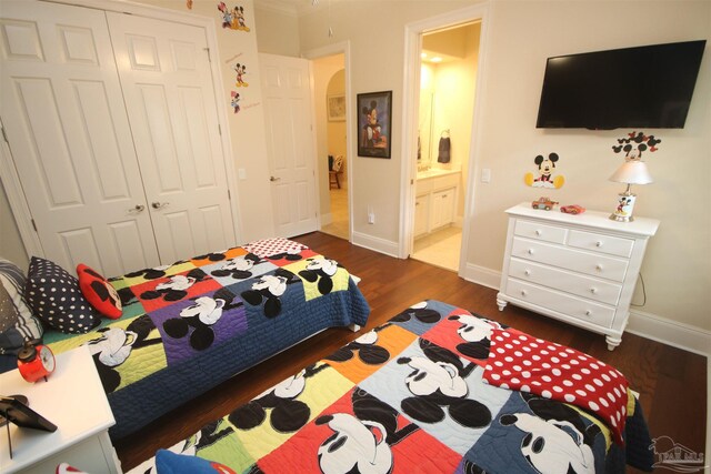 bedroom with ensuite bath, baseboards, a closet, and dark wood-style flooring