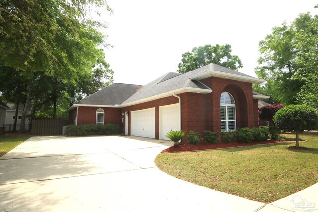 view of property exterior with driveway, fence, brick siding, an attached garage, and a lawn