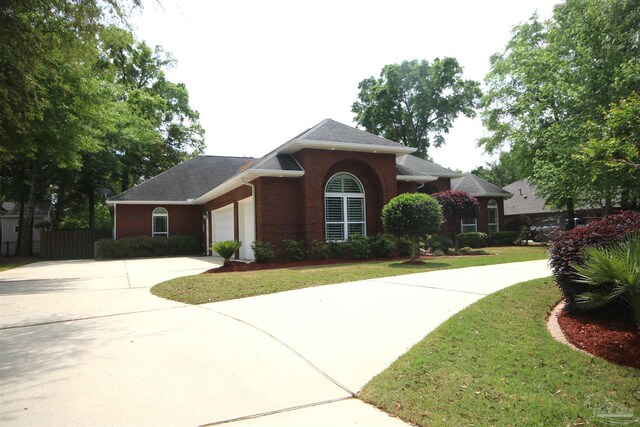 view of front facade with fence, a front lawn, driveway, brick siding, and a garage