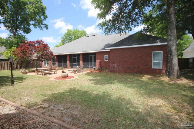 rear view of house with a yard, fence private yard, a patio, a sunroom, and brick siding