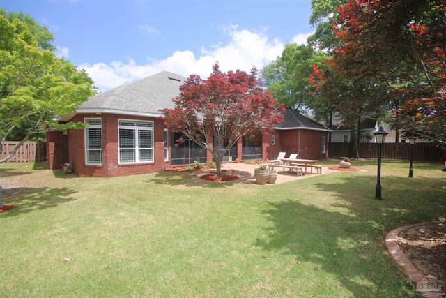 rear view of property with brick siding, a yard, fence private yard, and a patio