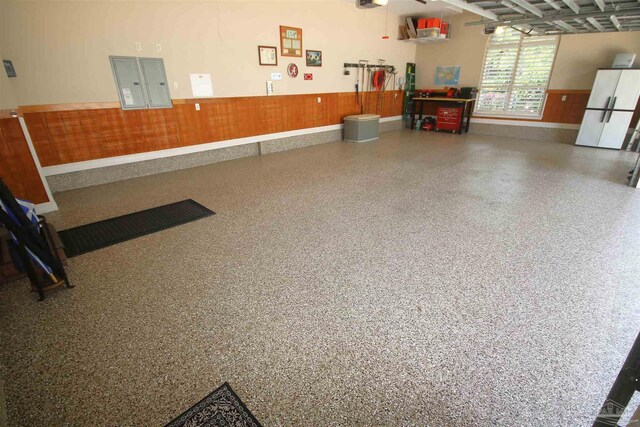garage with baseboards, a wainscoted wall, and freestanding refrigerator