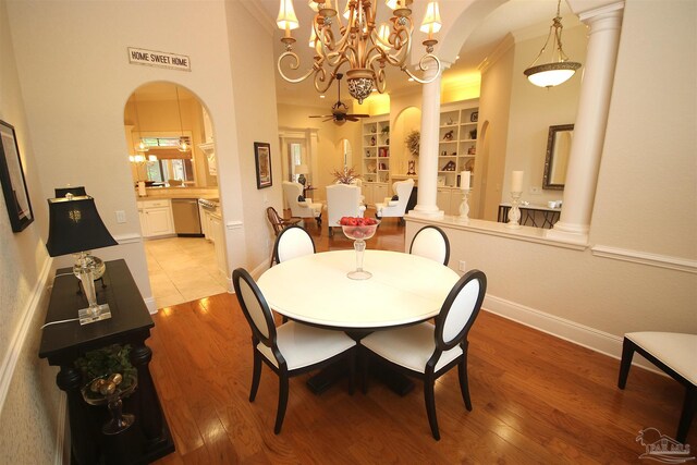 dining area featuring light wood finished floors, arched walkways, a notable chandelier, and built in shelves