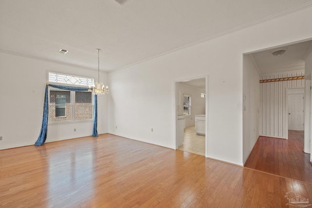 spare room with hardwood / wood-style floors, a chandelier, and ornamental molding