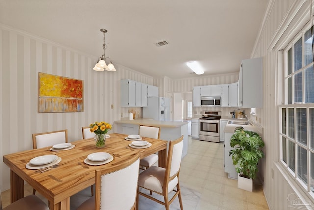 dining area featuring sink, an inviting chandelier, and crown molding