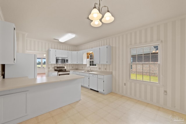 kitchen with appliances with stainless steel finishes, crown molding, a notable chandelier, white cabinets, and decorative light fixtures