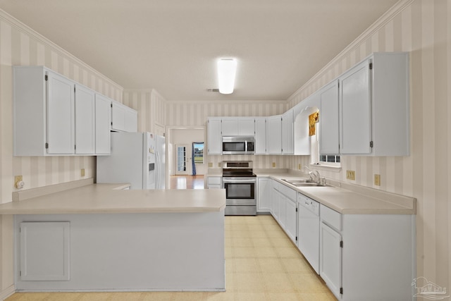 kitchen with stainless steel appliances, kitchen peninsula, ornamental molding, white cabinets, and sink