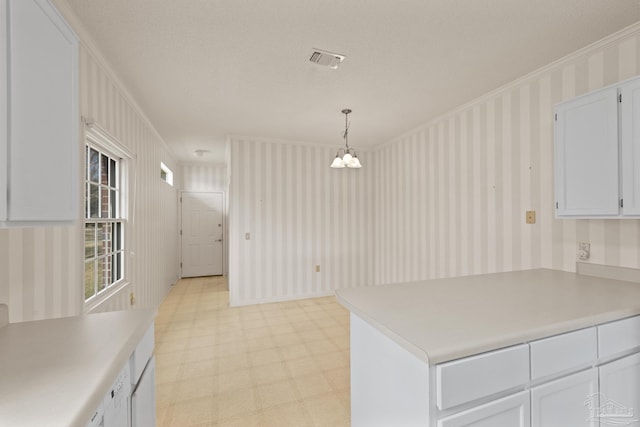 kitchen with white cabinets, a notable chandelier, decorative light fixtures, and ornamental molding