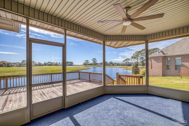 unfurnished sunroom featuring ceiling fan and a water view