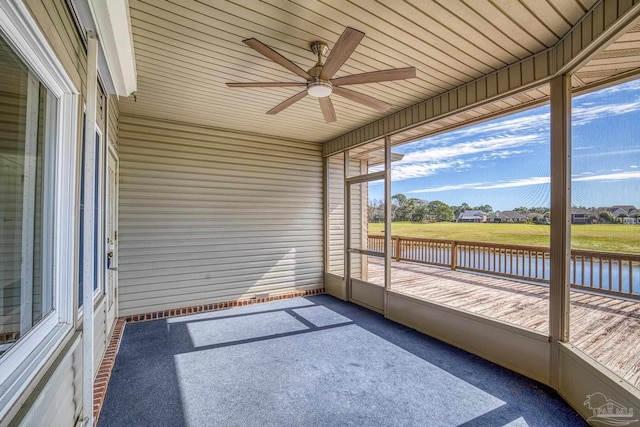 unfurnished sunroom with ceiling fan, wood ceiling, and a water view