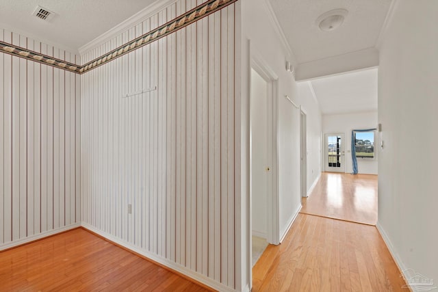 corridor featuring a textured ceiling, light hardwood / wood-style flooring, and crown molding