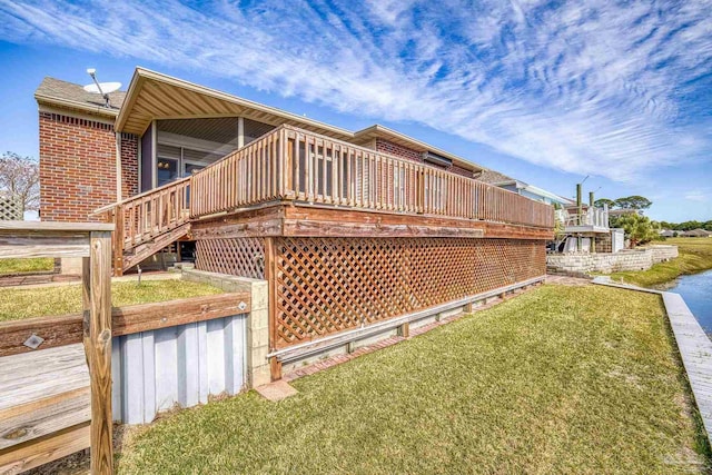 back of property with a deck and a lawn