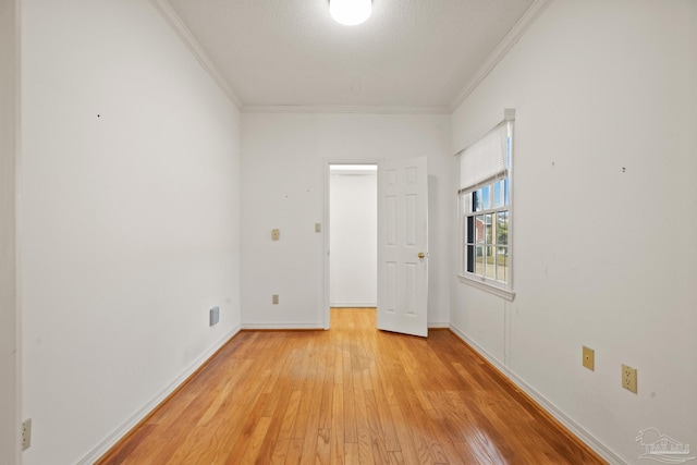 unfurnished room featuring a textured ceiling, ornamental molding, and light hardwood / wood-style flooring