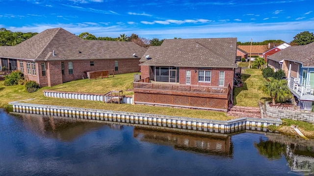 back of house with a yard, a water view, and a sunroom