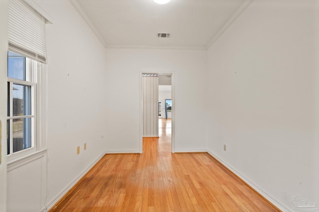 spare room featuring a textured ceiling, light hardwood / wood-style floors, and crown molding