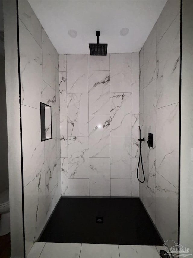 bathroom featuring a tile shower and toilet