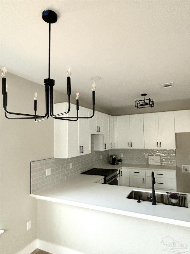 kitchen with tasteful backsplash, sink, decorative light fixtures, and white cabinets