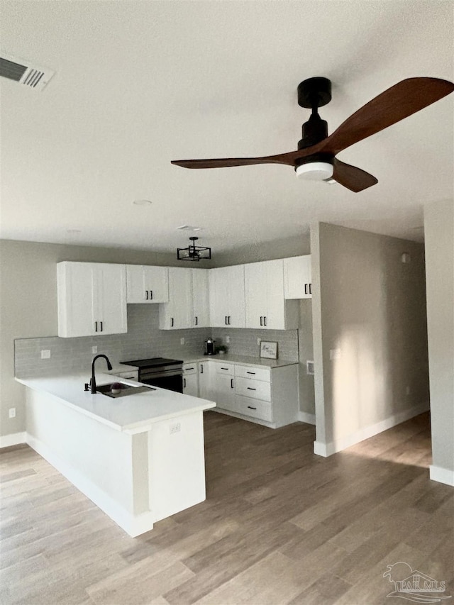 kitchen featuring white cabinetry, sink, backsplash, ceiling fan, and kitchen peninsula