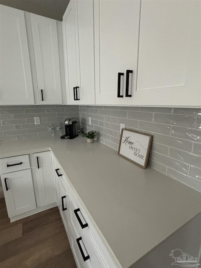 interior details with dark wood-type flooring, white cabinets, and backsplash