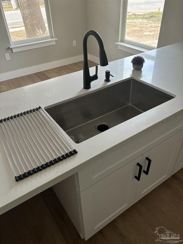 room details featuring sink, dark hardwood / wood-style floors, and white cabinets