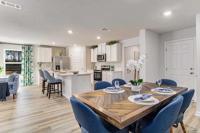 dining area featuring light hardwood / wood-style flooring and a textured ceiling