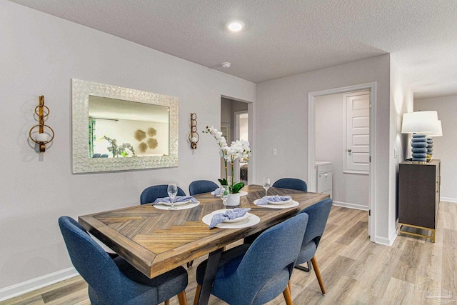 dining room with a textured ceiling and light hardwood / wood-style flooring