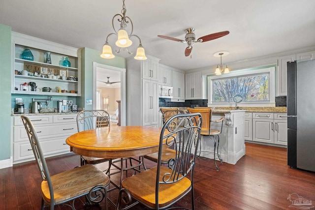 dining room featuring ceiling fan with notable chandelier, sink, and dark hardwood / wood-style flooring