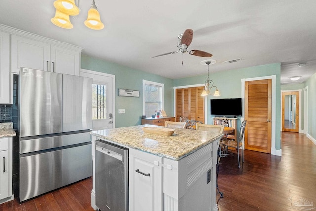 kitchen with ceiling fan with notable chandelier, light stone countertops, pendant lighting, white cabinets, and appliances with stainless steel finishes