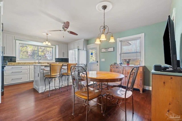 dining area with dark wood-type flooring, a wealth of natural light, and ceiling fan with notable chandelier