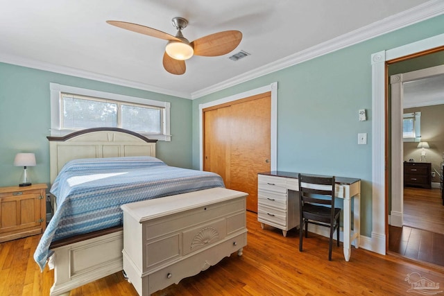 bedroom with ceiling fan, ornamental molding, a closet, and wood-type flooring