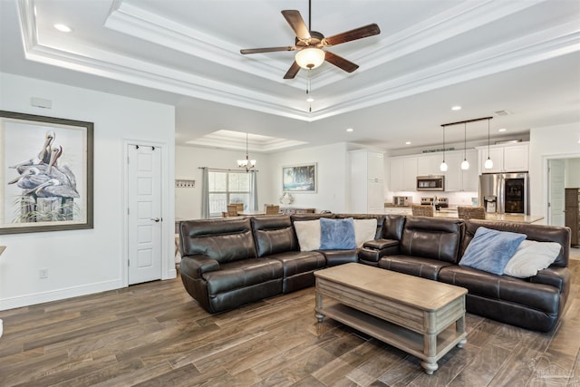 living room with crown molding, a tray ceiling, ceiling fan with notable chandelier, and dark hardwood / wood-style flooring