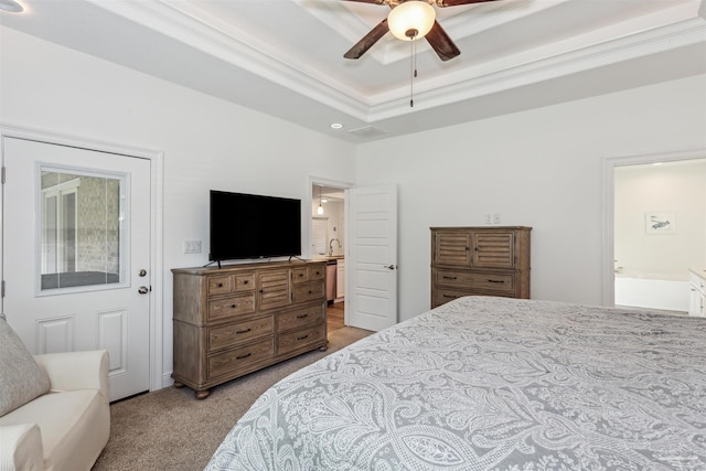 bedroom with light carpet, a tray ceiling, connected bathroom, ornamental molding, and ceiling fan