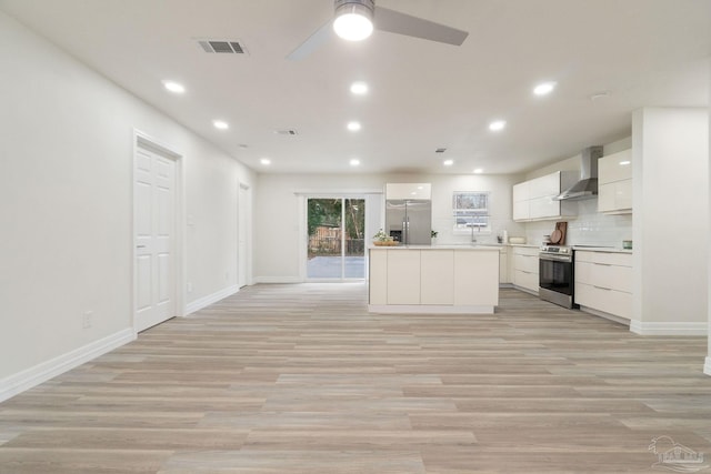 kitchen featuring modern cabinets, wall chimney range hood, light countertops, appliances with stainless steel finishes, and white cabinetry