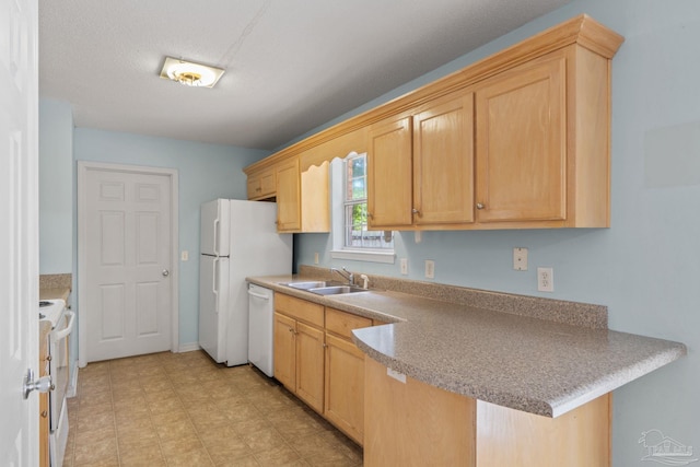 kitchen with a sink, light brown cabinets, a peninsula, and white appliances