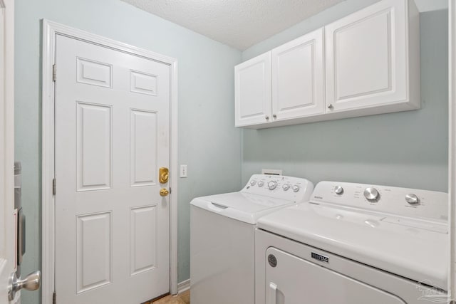 washroom with a textured ceiling, cabinet space, and washer and dryer