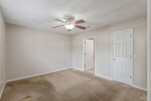 carpeted spare room featuring baseboards, a ceiling fan, a textured ceiling, and visible vents