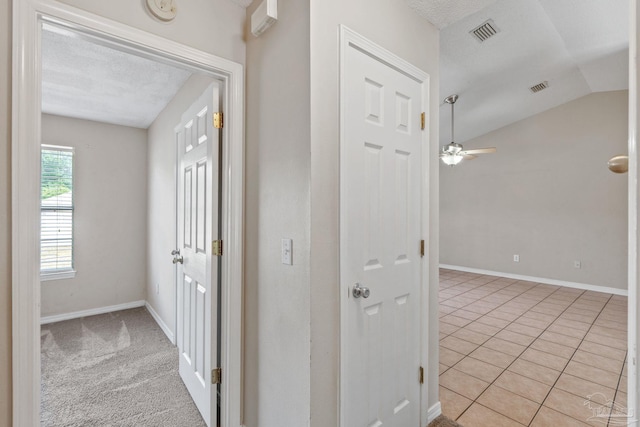 hall featuring visible vents, baseboards, light tile patterned floors, and vaulted ceiling