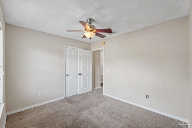 unfurnished bedroom with carpet floors, visible vents, baseboards, ceiling fan, and a textured ceiling