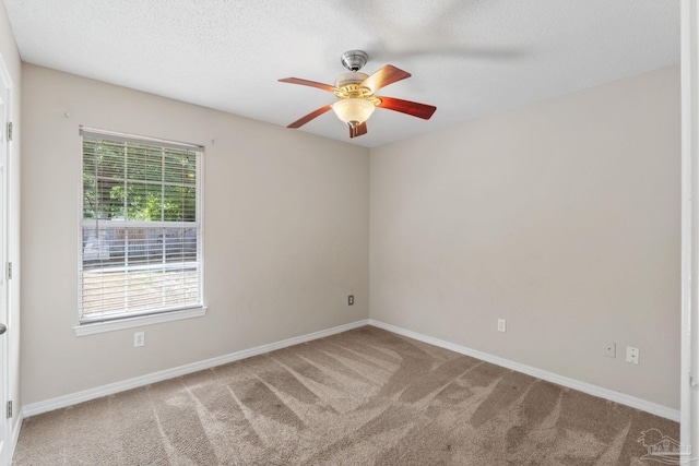 empty room with carpet floors, baseboards, a ceiling fan, and a textured ceiling