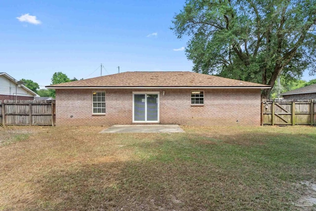 back of property featuring brick siding, a fenced backyard, a lawn, and roof with shingles