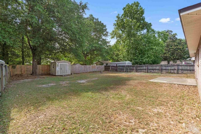 view of yard featuring a fenced backyard, a storage unit, and an outbuilding