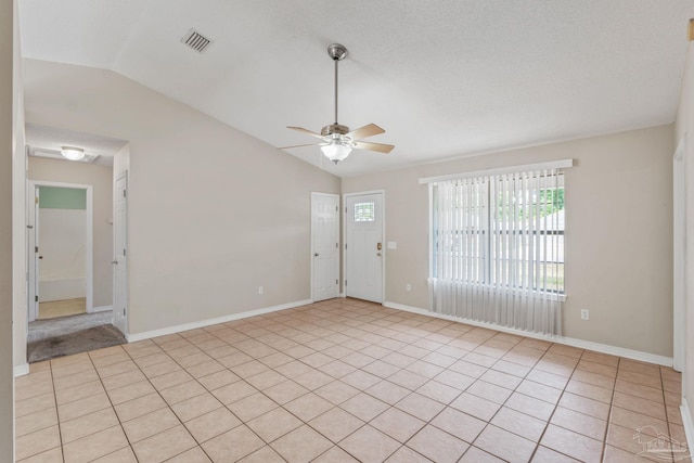 unfurnished room featuring visible vents, a ceiling fan, baseboards, light tile patterned floors, and vaulted ceiling