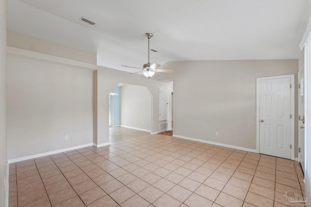 spare room featuring visible vents, lofted ceiling, light tile patterned flooring, ceiling fan, and arched walkways