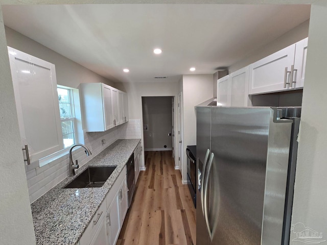 kitchen featuring backsplash, sink, stainless steel refrigerator with ice dispenser, light hardwood / wood-style flooring, and white cabinetry